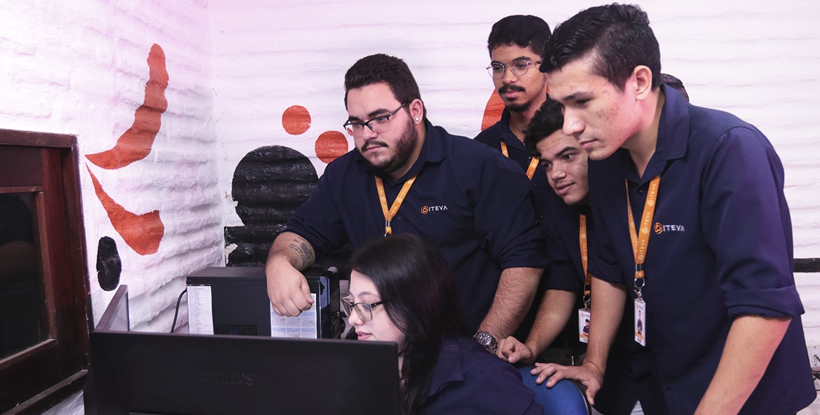 Equipe de desenvolvimento de software reunidos com uma pessoa sentada de frente para o computador