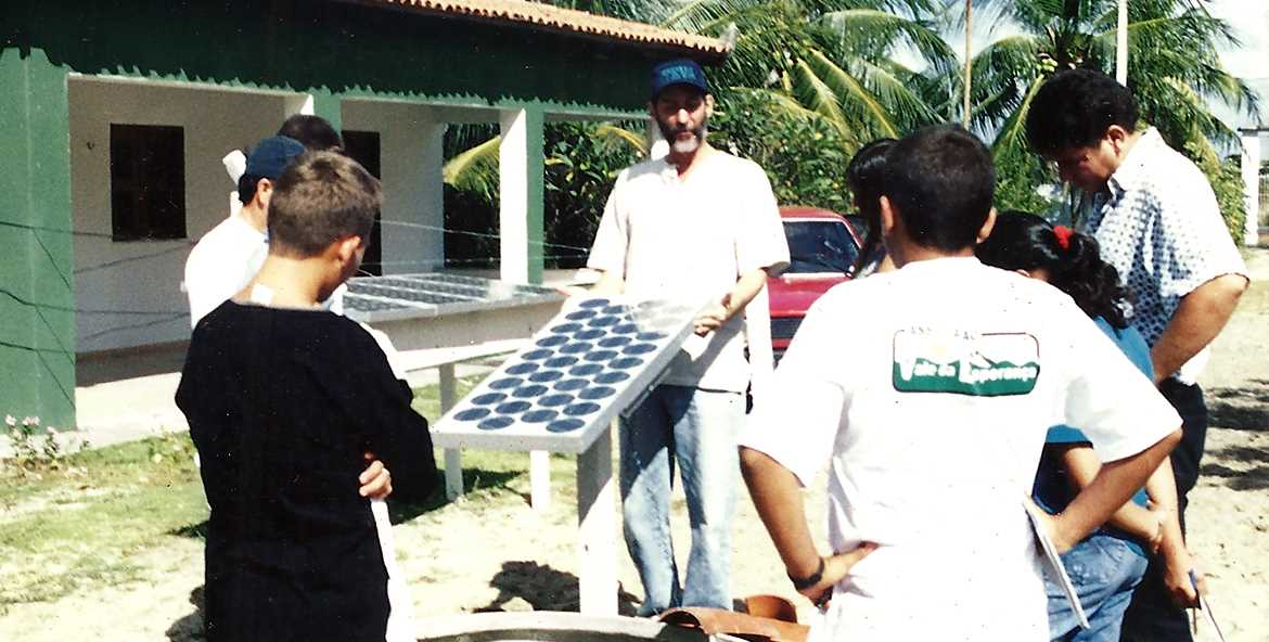 Várias pessoas ao ar livre ouvindo uma explicação sobre placas fotovoltaicas
