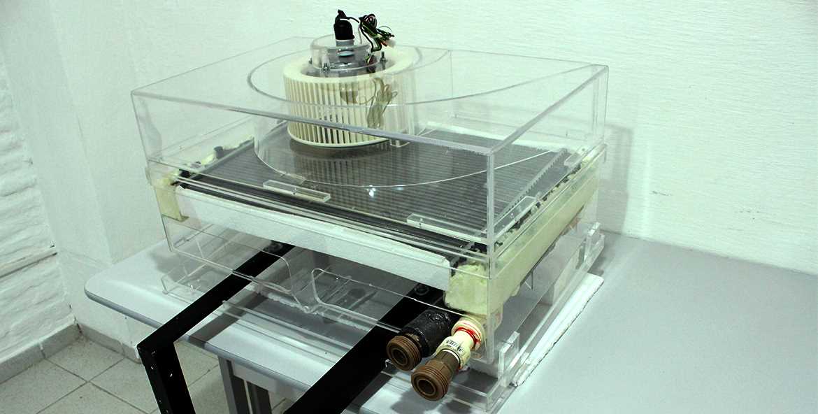 Modelo de fan coil caseiro feito com radiador automotivo e coberto com acrílico exposto em uma mesa